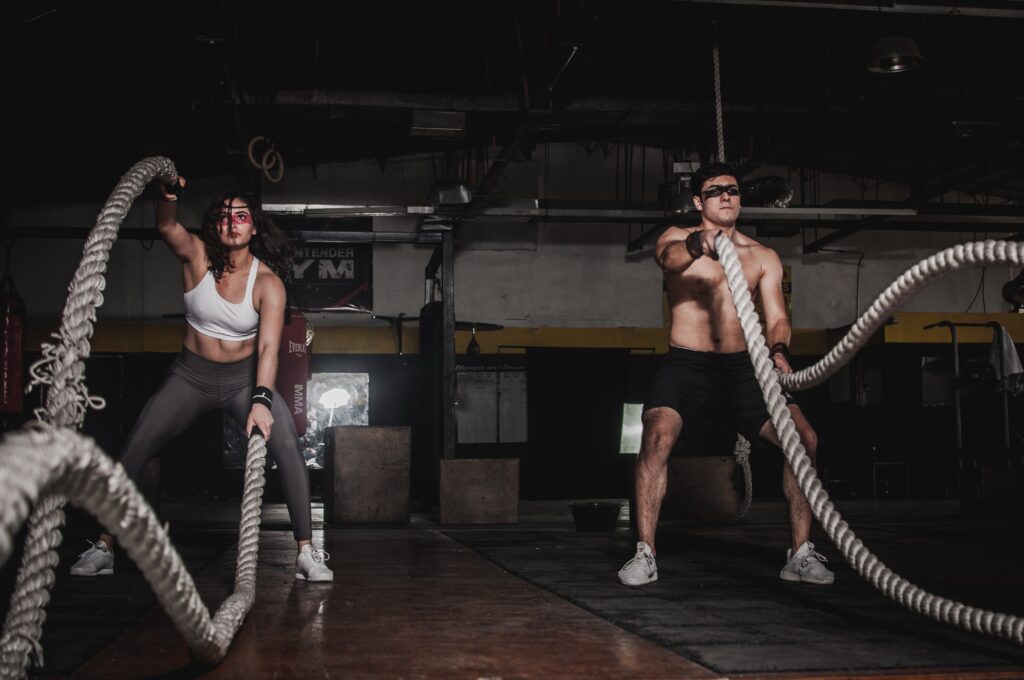 Men And Women Holding Rope In Gym.